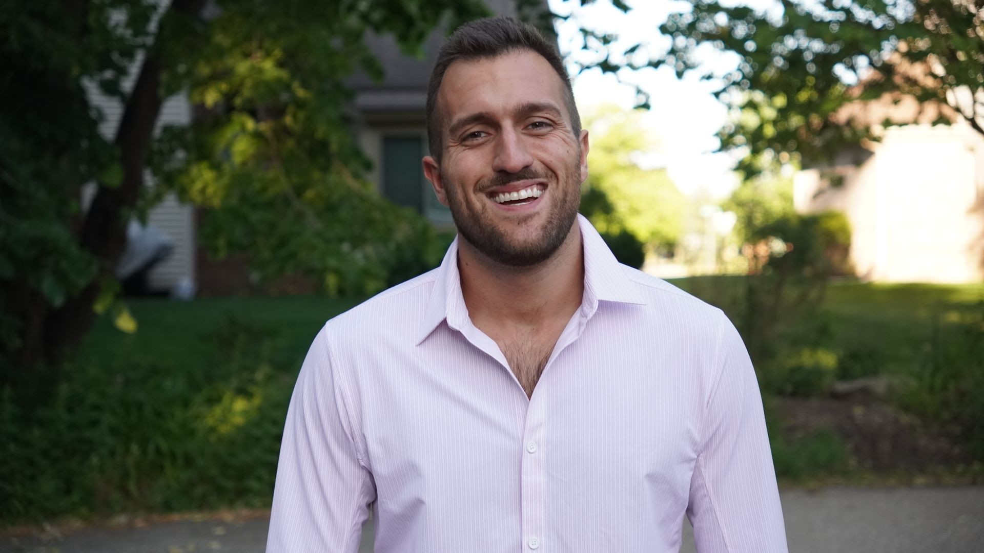 Brandon Kaitschuck, Chief Relationship Officer and cybersecurity expert, smiling outdoors in a professional headshot, wearing a light purple shirt with trees and greenery in the background